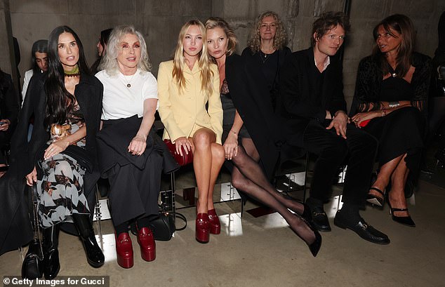 Kate walked away from Nikolai as she hugged her daughter Lila as the couple sat front row at the fashion show, leaving him talking to her mother, the elegant Jane von Bismarck (right).