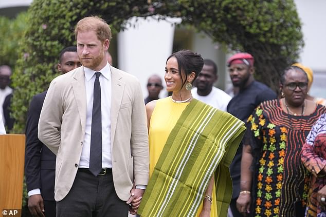 Prince Harry, left, and Meghan, right, hold hands as they arrive at Government House in Lagos, Nigeria, on Sunday, May 12.