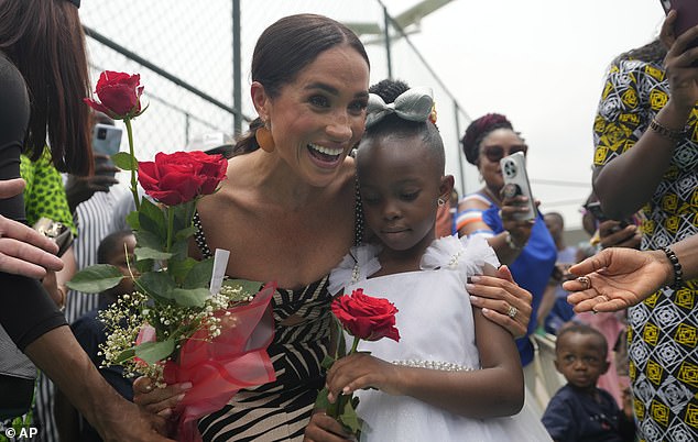 Meghan smiles as she receives flowers during a sitting volleyball match in Abuja on May 11.