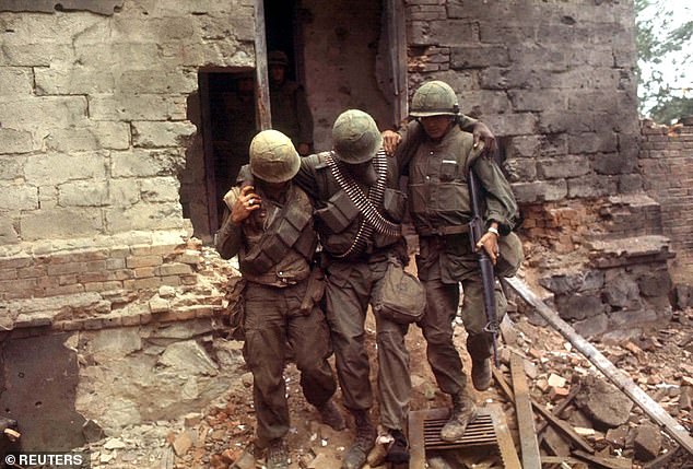 In this file photo, two U.S. Marines support a wounded soldier as he leaves a building that was attacked, February 6, 1968 in South Vietnam.