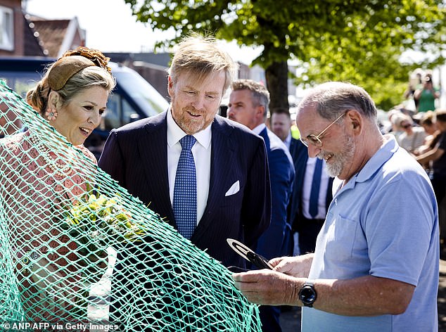 Queen Máxima talks to a man fixing a net during a visit to Zoutkamp, ​​near Groningen.