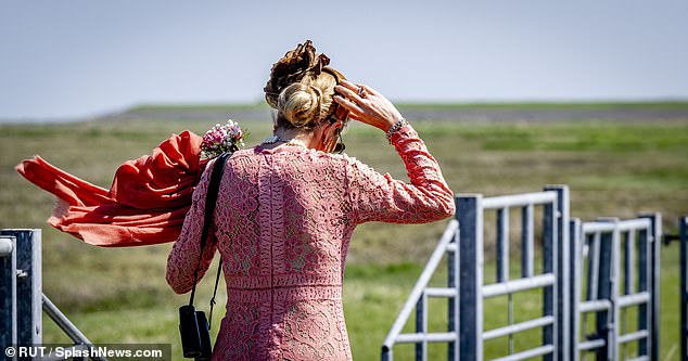 Máxima held on to her headband as she walked through the field in windy weather.