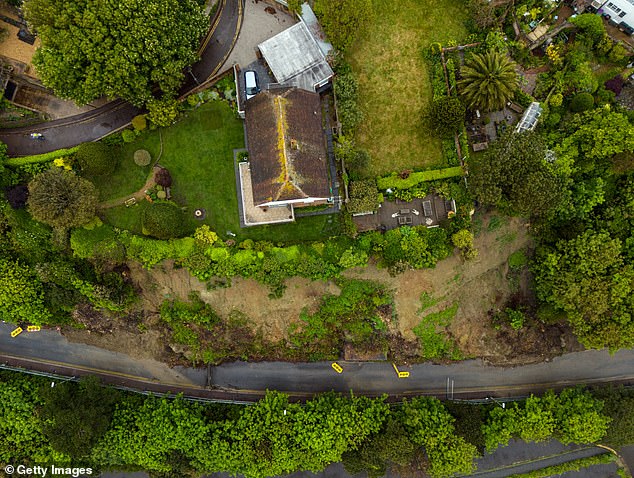 In this aerial view, a house sits near the edge of a cliff after a landslide eroded part of the cliff.