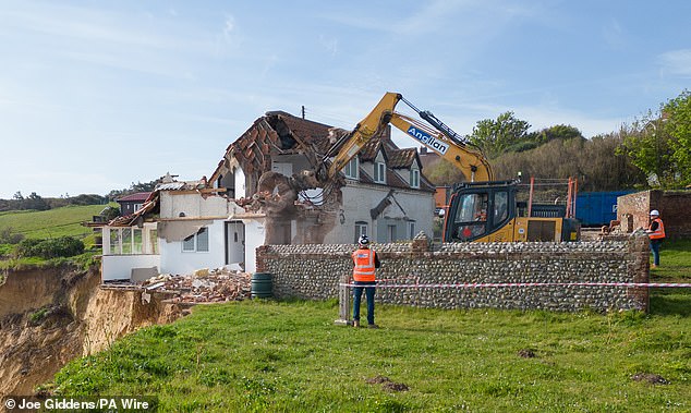 Last week in Norfolk, a 200-year-old three-bedroom property (pictured) hanging perilously over the edge of a 150ft cliff on the coast was demolished in less than three hours.