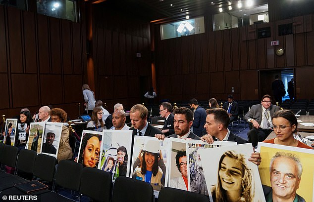 Relatives hold photos of victims of the Boeing 737 MAX crash as they wait for Boeing CEO Dennis Muilenburg to testify before a Senate hearing in Washington, Oct. 29, 2019.