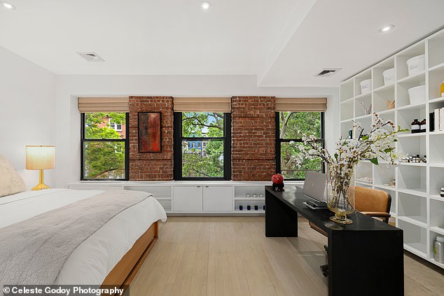 The master bedroom features a long study desk, floor-to-ceiling shelves, and three windows with light brown blinds.