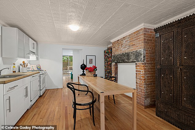 The living room in front of the kitchen is adorned with white planes and sheets of white panels, suspended from wooden beams.