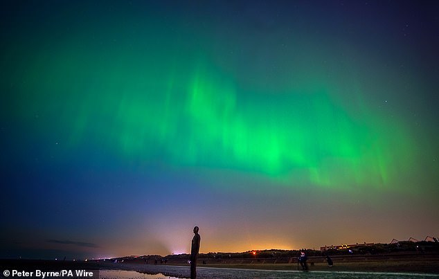 LIVERPOOL: The Northern Lights shine on the horizon of Anthony Gormley's Another Place sculpture on Crosby Beach in Liverpool