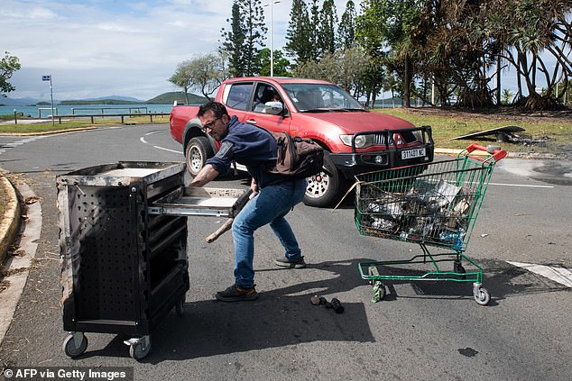 A local resident clears the roads of burned debris left by rioters.