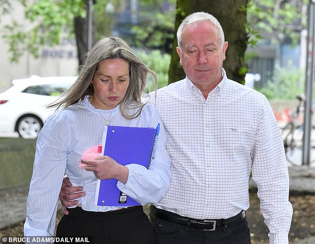 TODAY: Rebecca Joynes, 30, hung her head as she arrived at Manchester Crown Court and clutched the knitted garment behind a purple notebook as her father put his arm around his daughter's waist.