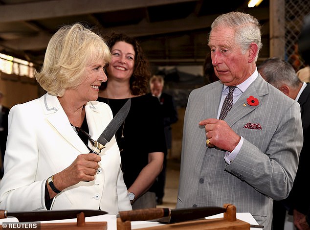 A smiling Camilla surprises Charles by holding a large knife in the air during a visit to a winery in Australia.