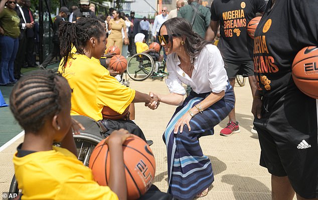 Meghan Markle, center, shakes hands with a girl in a wheelchair during the African Giant Foundation at the Dream Big Basketball clinic in Lagos, Nigeria, Sunday, May 12, 2024.