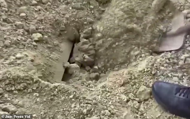 Officers are seen removing the man from the makeshift grave.