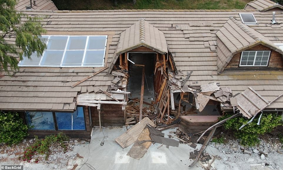 The area surrounding the main house on the property is unkempt with patches of dry grass and piles of dirt or sand.