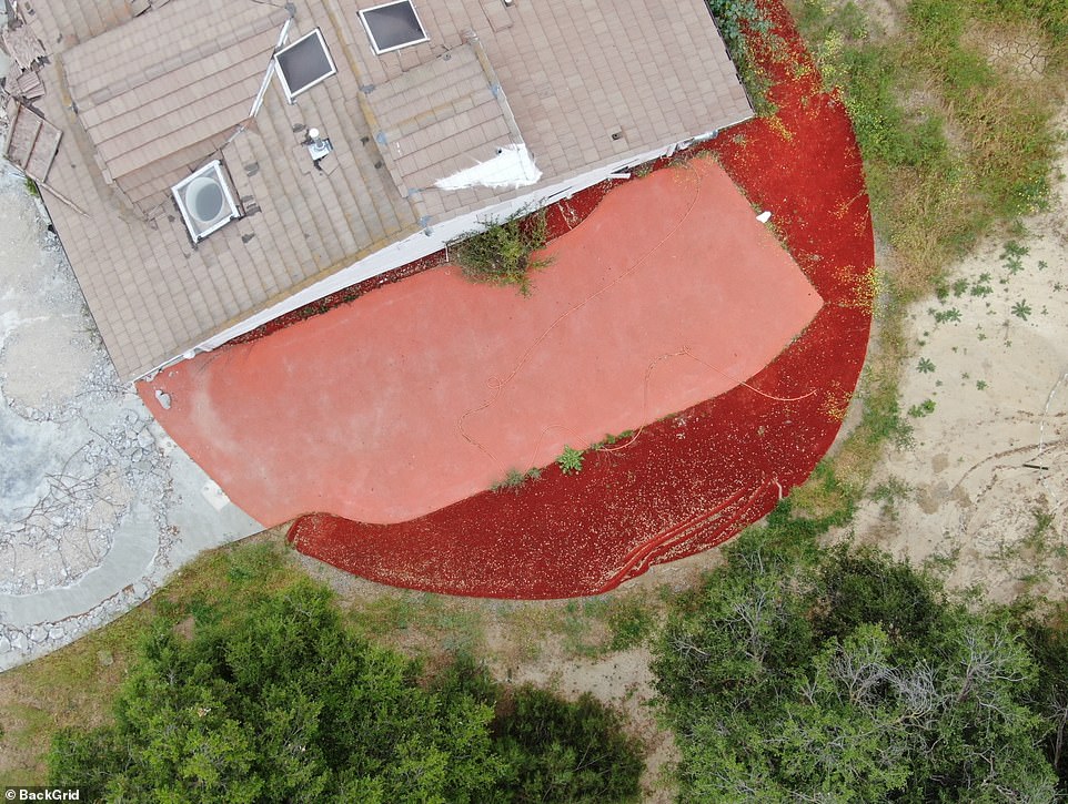 Parts of the concrete driveway are dismantled, while one side of the property is partially hidden by a red covering.