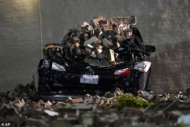 A car crushed by bricks falling from the wall of a fallen building sits in a downtown Houston parking lot.