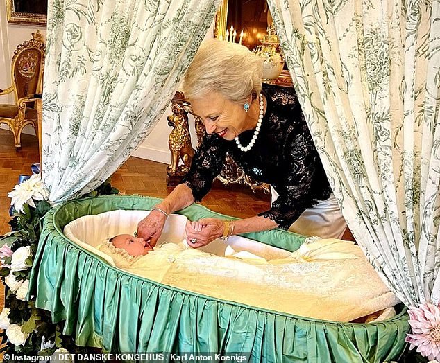 Another sweet photo shows Princess Benedikte admiring her grandson on a cot while lovingly pinching his cheek at last year's christening.