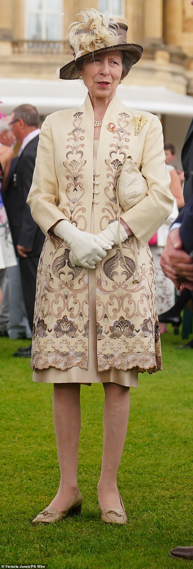 Anne paired this statement piece with a matching eggshell-colored wide-brimmed hat with feathers on top and a classic brown dress that fell just above the knee.