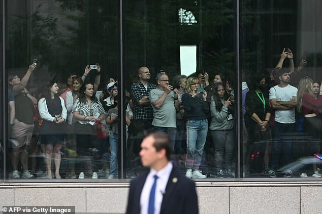 People watch the motorcade carrying President Joe Biden near the National Museum of African American History and Culture.