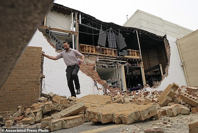 A man walks on fallen bricks from a damaged building in the chaotic scenes caused by the storm