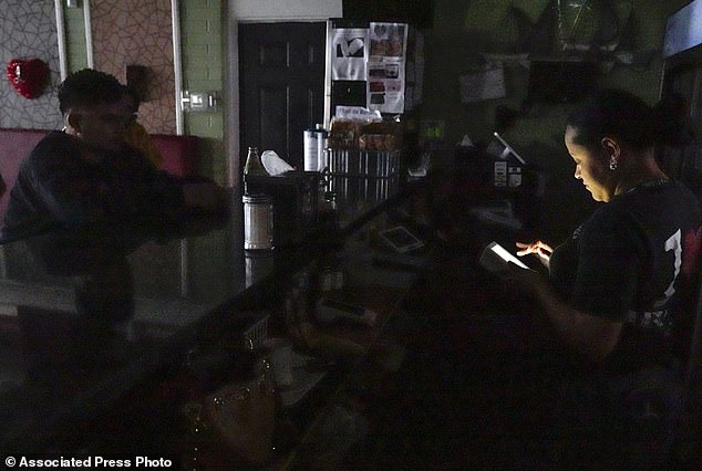 Ada Duarte takes takeout orders using only the light on her phone after losing power at Anita's Honduras restaurant on Sowden Road following the storm.