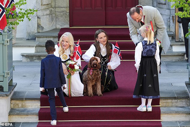 The royal couple were also joined by their daughter Princess Ingrid Alexandra, 20, (centre) and their dog Molly as they waved at the children's parade.