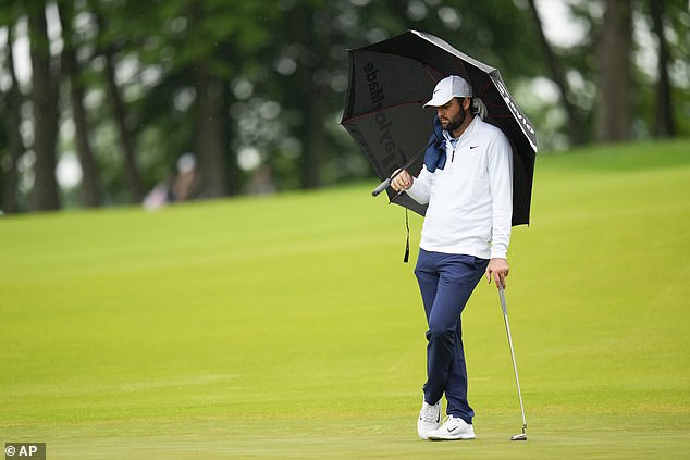 The world number one protects himself from the rain