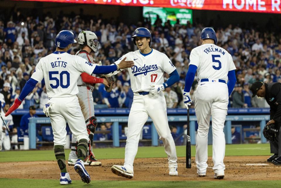 Dodgers star Shohei Ohtani is greeted by Mookie Betts and Freddie Freeman after hitting a two-run home run.