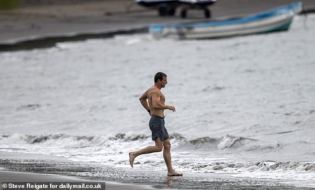 Grylls was seen running topless and wearing gray swim shorts while diving into the sea.