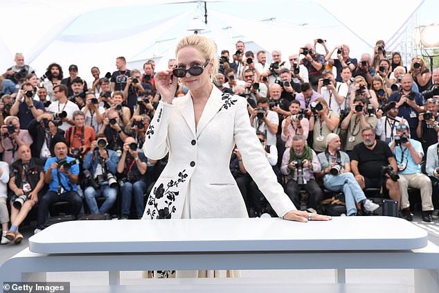 Uma stylishly pulled down her sunglasses while standing behind a huge podium.