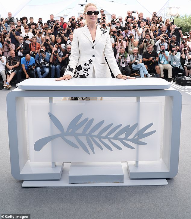 The podium featured the Cannes leaf symbol on the front and behind Uma was a wall of photographers.