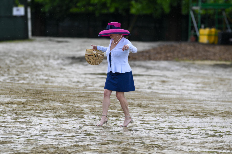 A woman walks through the mud to reach the grandstand before the Preakness Stakes horse race at Pimlico Race Course, Saturday, May 18, 2024, in Baltimore. (AP Photo/Nick Wass)