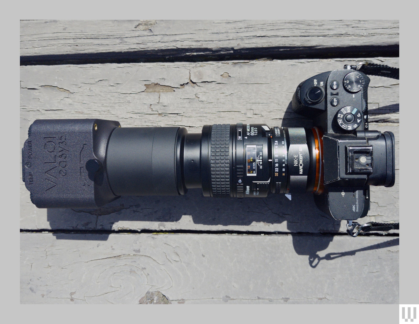 Overhead view of a digital camera with a long black lens attachment attached to a small black plastic case