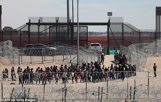 Migrants queuing to be transported by US Border Patrol on April 18, 2024 after crossing the Rio Grande in El Paso, TX