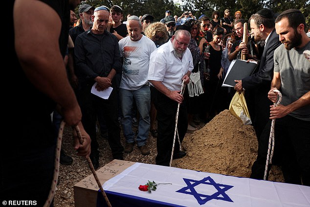 Mourners lower Shani's coffin into the grave last night during his funeral in Srigim.