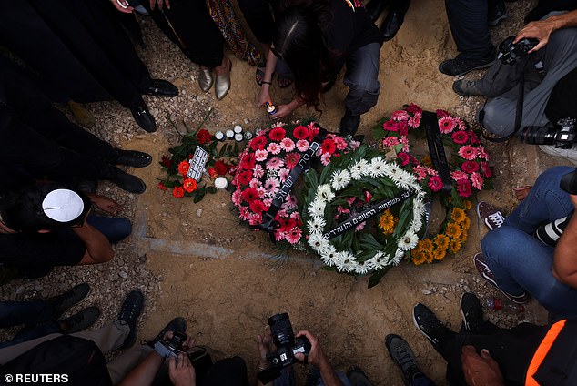 Mourners gather near the grave of German-Israeli Shani and lay flowers on the ground.