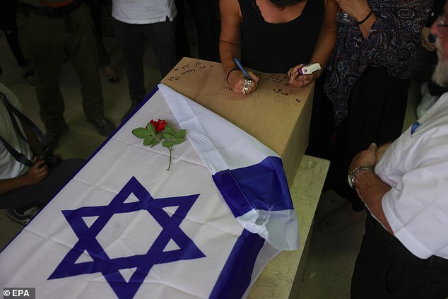 In the photo, relatives and relatives write on the coffin during last night's funeral.