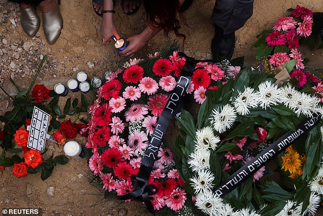 A mourner lights a candle yesterday near Shani's grave, laden with floral tributes.