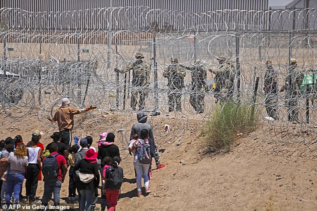 Texas National Guard agents use pepper spray to deter migrants at a barbed wire fence installed along the Rio Grande.