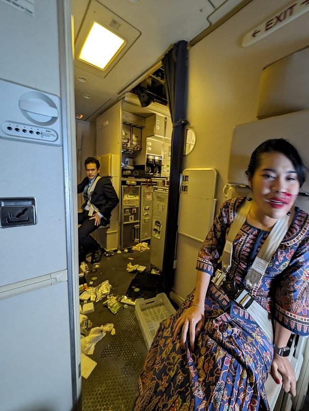 A passenger on board a Singapore Airlines plane from the UK has described the extreme turbulence that killed a fellow passenger in a tragic incident today. Pictured: The crew is seen after extreme turbulence on the Singapore Airlines plane today.