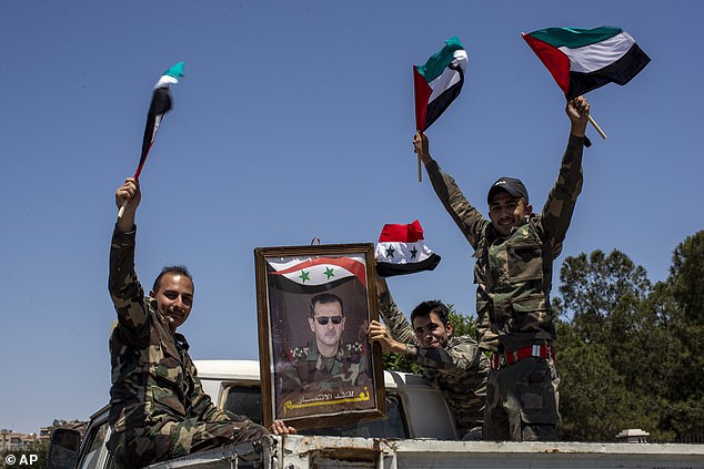 Syrian soldiers hold Baath Party flags and a portrait of Syrian President Bashar Assad in Arabic that reads 