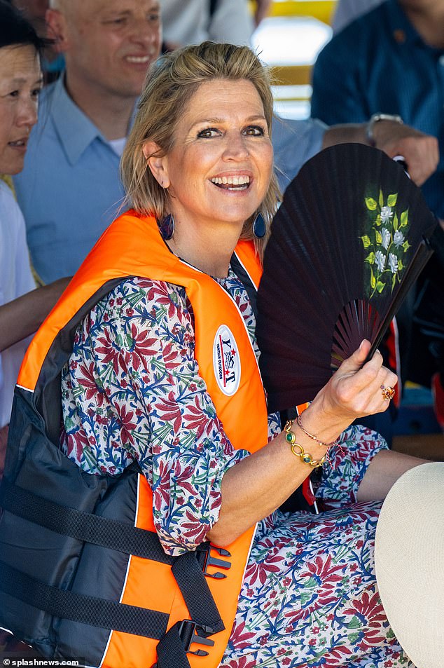 The Dutch royal, 53, donned a fluorescent life jacket for the trip to Talim Island and kept cool with a large fan.