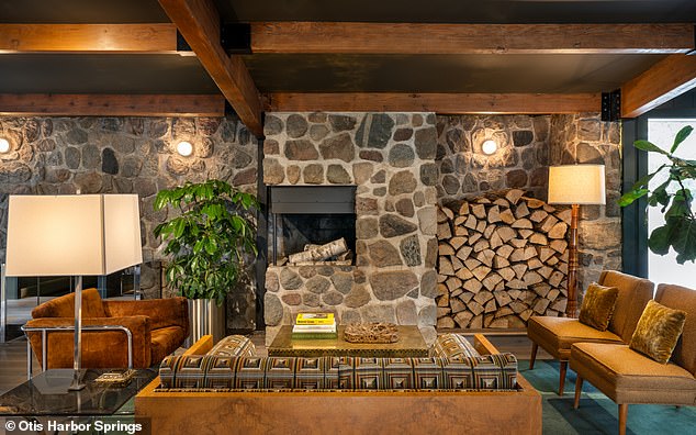 A large living room with fireplace is located in the center of the main lodge. The space has additional firewood available to light fresh fires and ample seating space for people to gather.