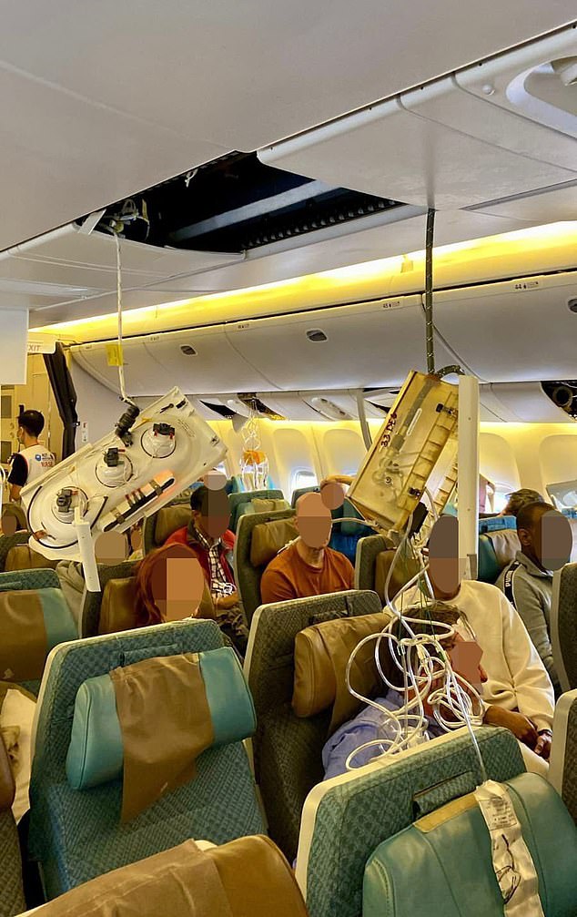 Passengers are seen on the Singapore Airlines plane after it made an emergency landing in Bangkok today. The oxygen masks fell from the ceiling, as did other components.