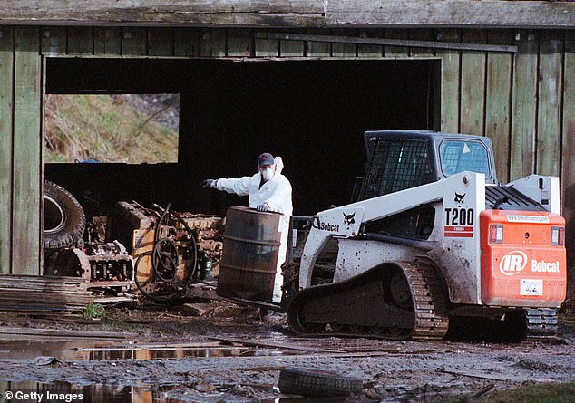 Royal Canadian Mounted Police investigators move debris at a pig farm February 19, 2002 in Port Coquitlam, British Columbia. The farm is currently being investigated for fifty missing women from the downtown Vancouver area.