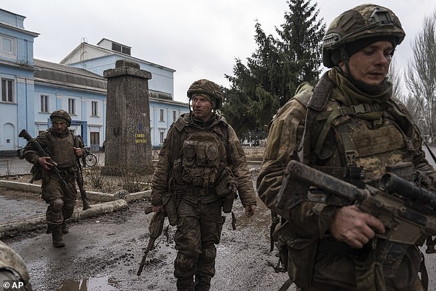 Ukrainian servicemen who recently returned from the Bakhmut trenches walk along a street in Chasiv Yar, Ukraine