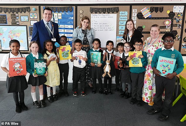 Princess Beatrice is pictured with some of the school children and teachers holding books.