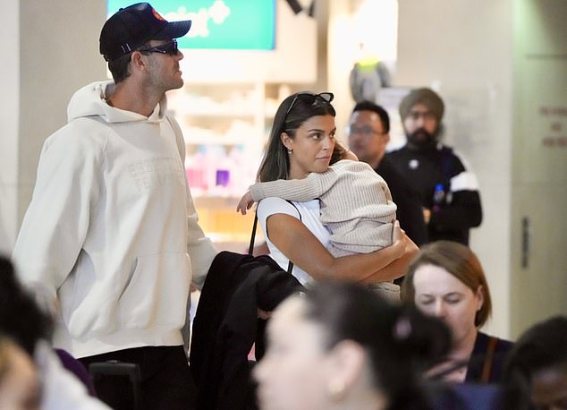 She finished her look with a pair of sneakers and was all smiles as she carried Posy through the airport while she slept.