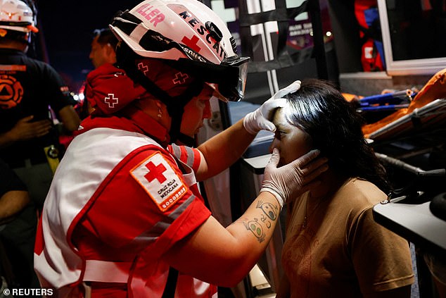 A Mexican Red Cross rescuer checks on a girl at the scene after a gust of wind caused a structure to collapse at a campaign rally.