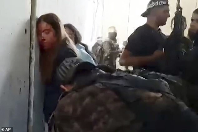 Israeli female soldiers from the Nahal Oz military base are placed against the wall and chained by Hamas members after being taken captive on October 7, 2023.